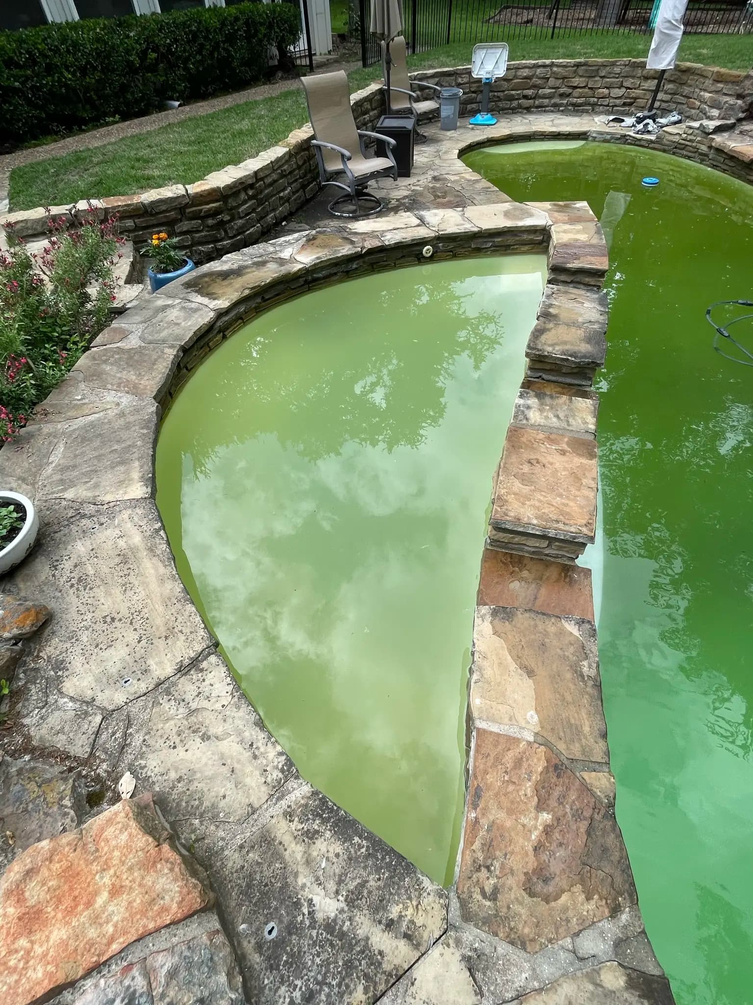 Shallow end of a green pool beside a raised spa, water still opaque