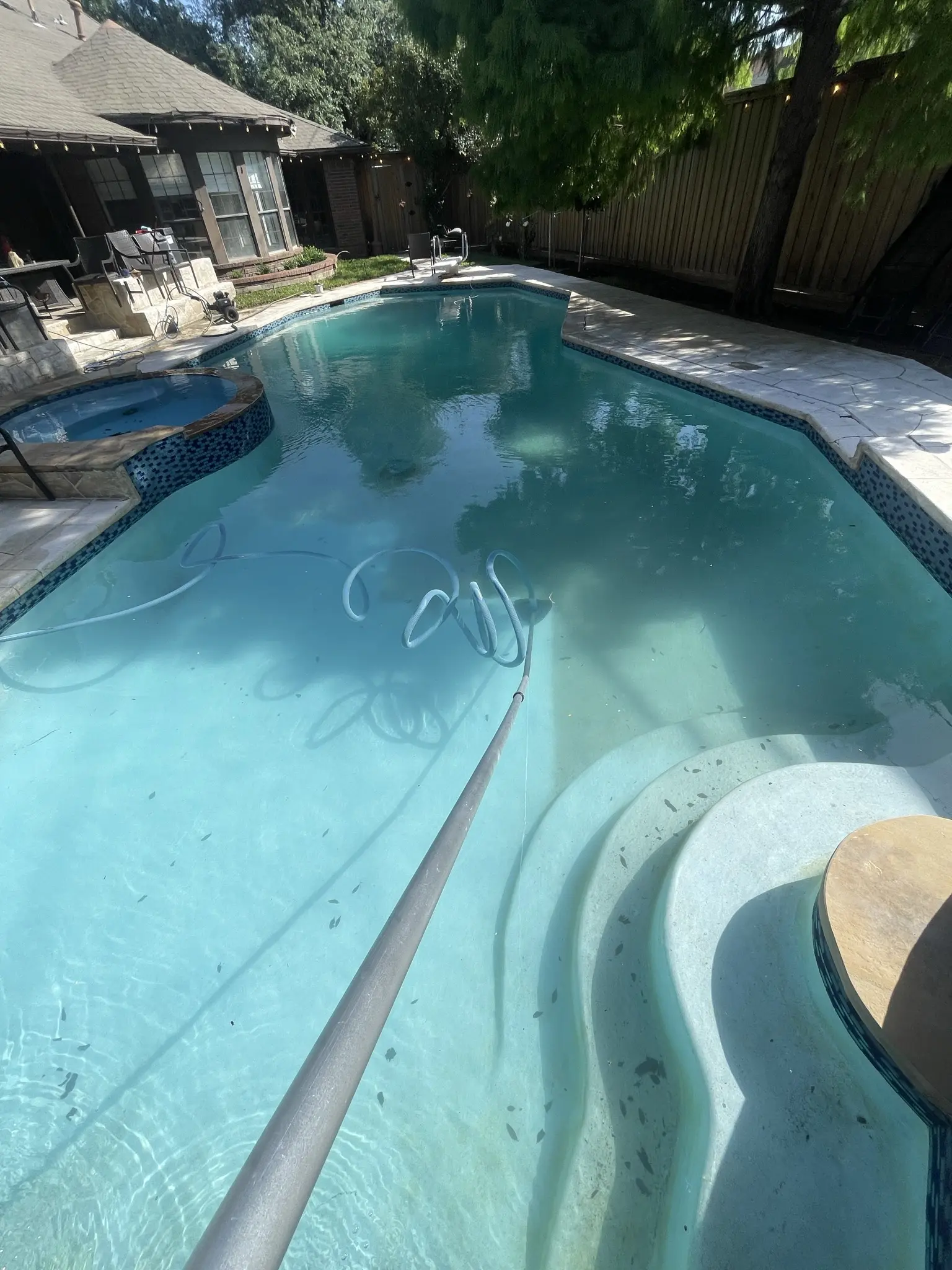 The same pool clearing further, the steps and spa now visible through the water