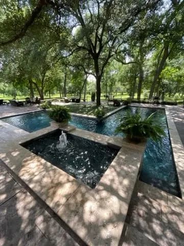 Formal garden pool with a dark water feature and a fountain under mature trees