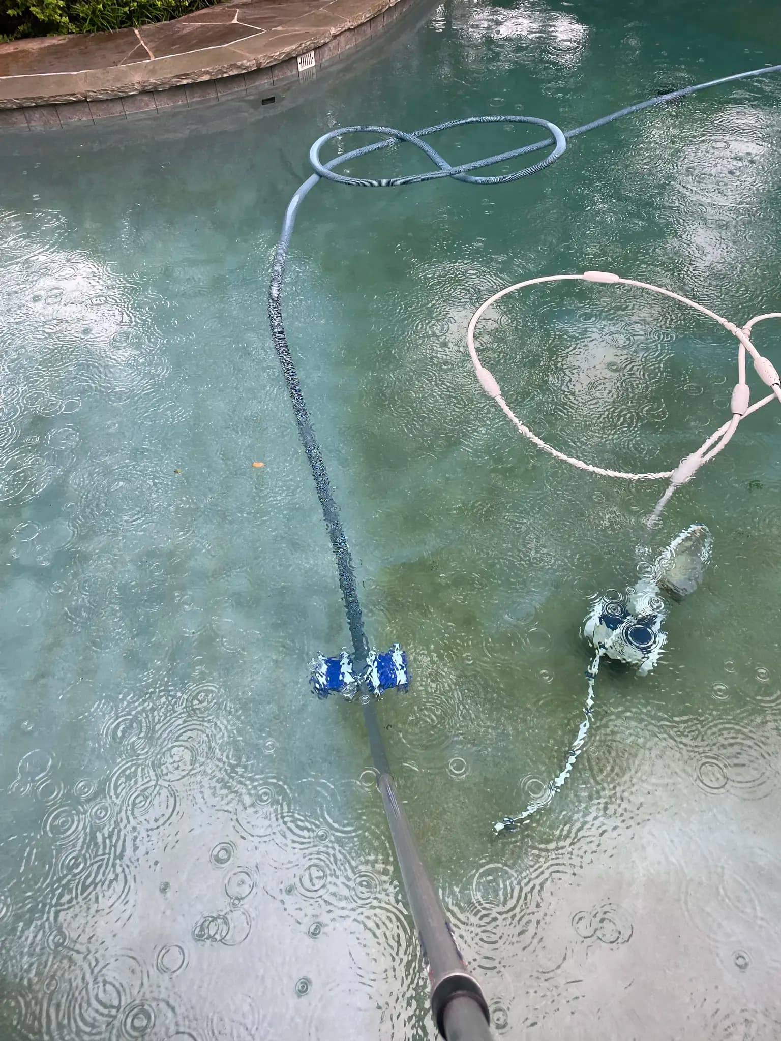 Pool technician vacuuming a pool in the rain